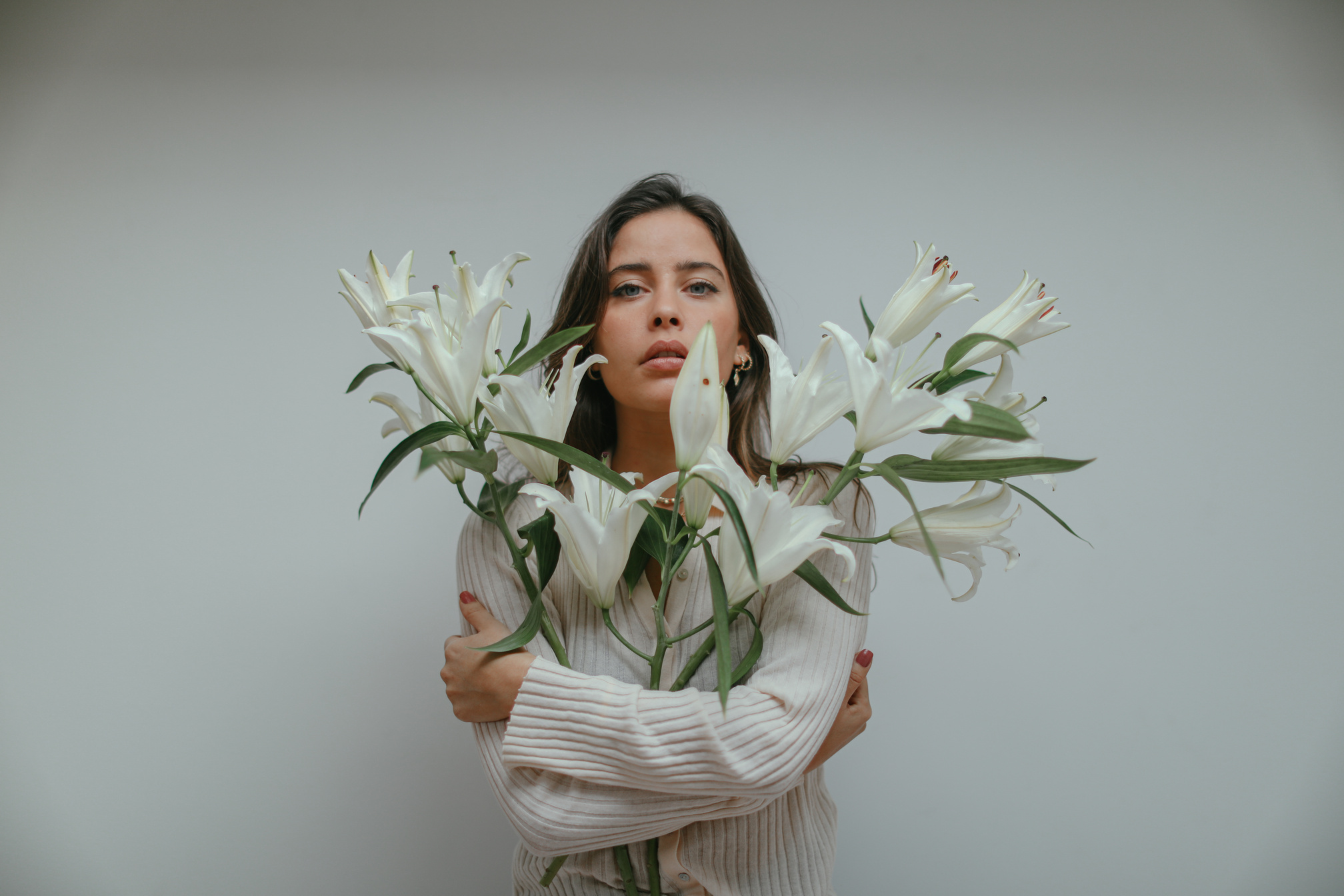 Woman Holding Stems of Beautiful White Lily Flowers